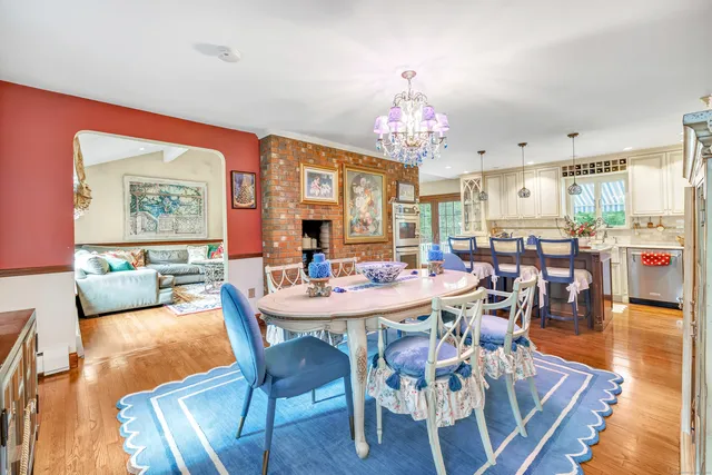 a living room with furniture a fireplace and a dining table with wooden floor