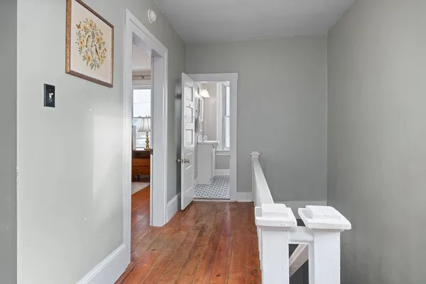 a view of a hallway with wooden floor and staircase