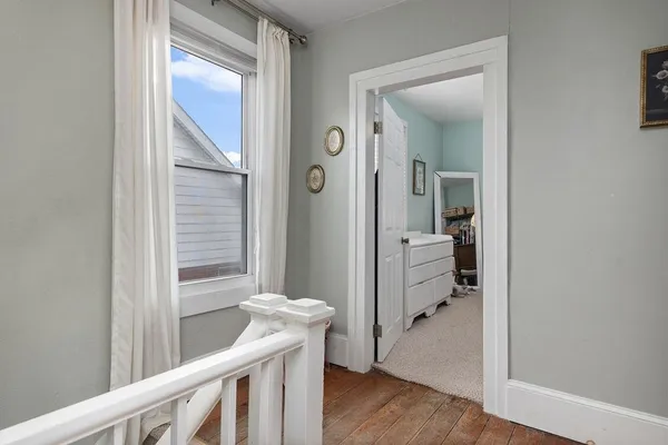 a view of a hallway with bathroom and wooden floor