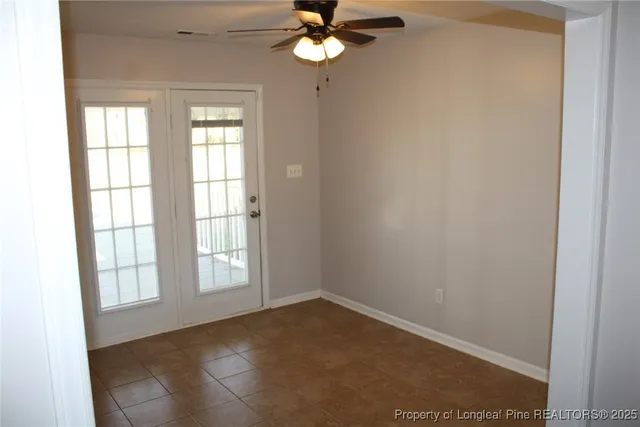 an empty room with windows and ceiling fan