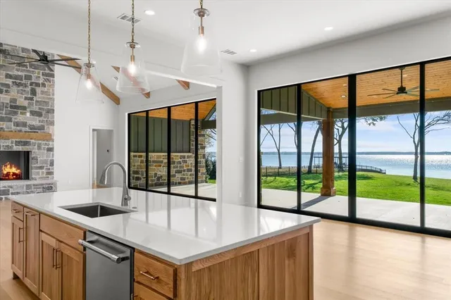 a kitchen with a stove a sink a large window and a wooden floor