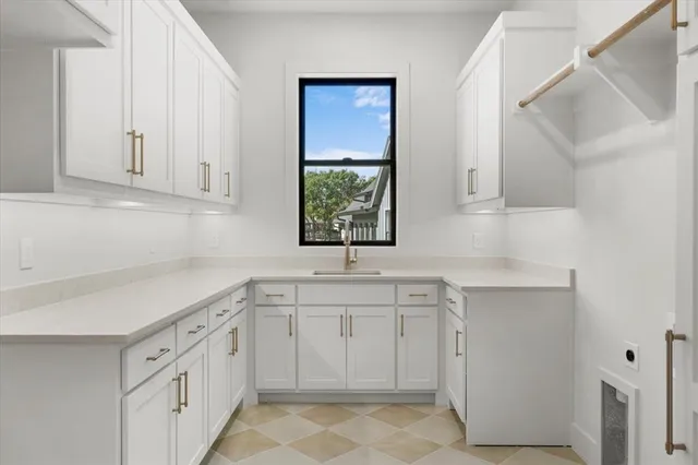 a kitchen with white cabinets sink and window