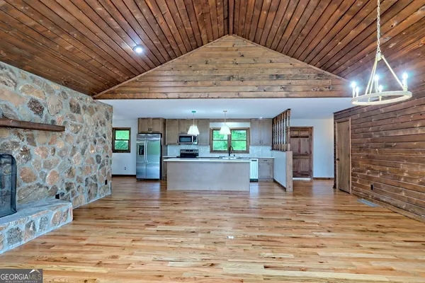 a kitchen with stainless steel appliances kitchen island granite countertop a refrigerator stove oven and white cabinets with wooden floor