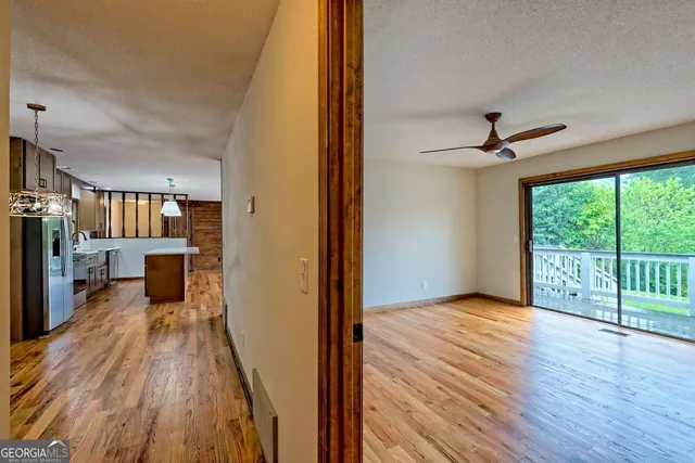 a view of an empty room with wooden floor and a window
