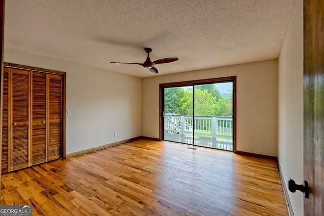 a view of empty room with wooden floor and fan