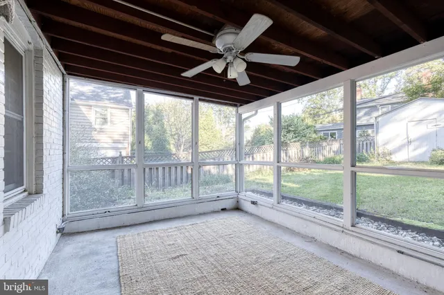 a view of an empty room with wooden floor and a ceiling fan