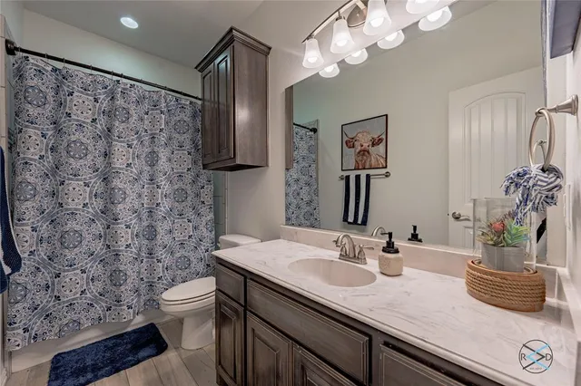 a bathroom with a granite countertop sink a toilet and a mirror
