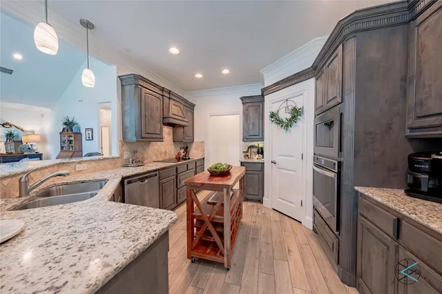 a kitchen with granite countertop kitchen island stainless steel appliances a stove top oven a sink a dining table and chairs