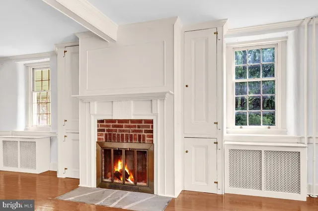 a view of an empty room with wooden floor fireplace and windows