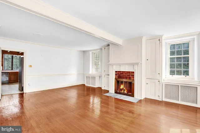 an empty room with wooden floor fireplace and windows