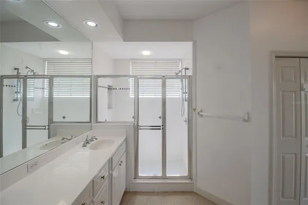 a bathroom with a mirror a double vanity sink and glass door shower