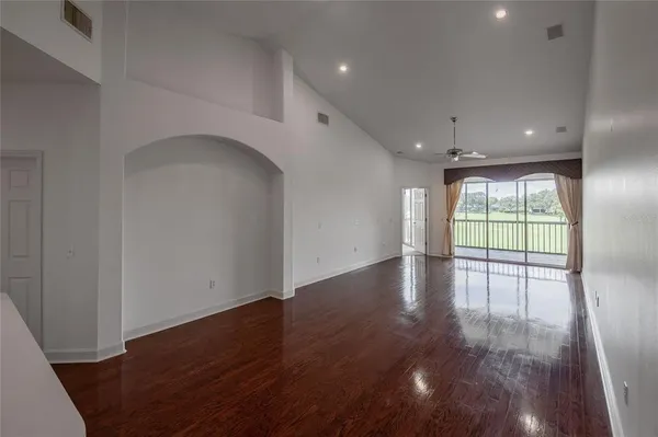 an empty room with wooden floor and windows