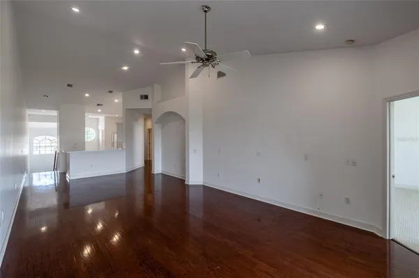 a view of an empty room with wooden floor and a ceiling fan
