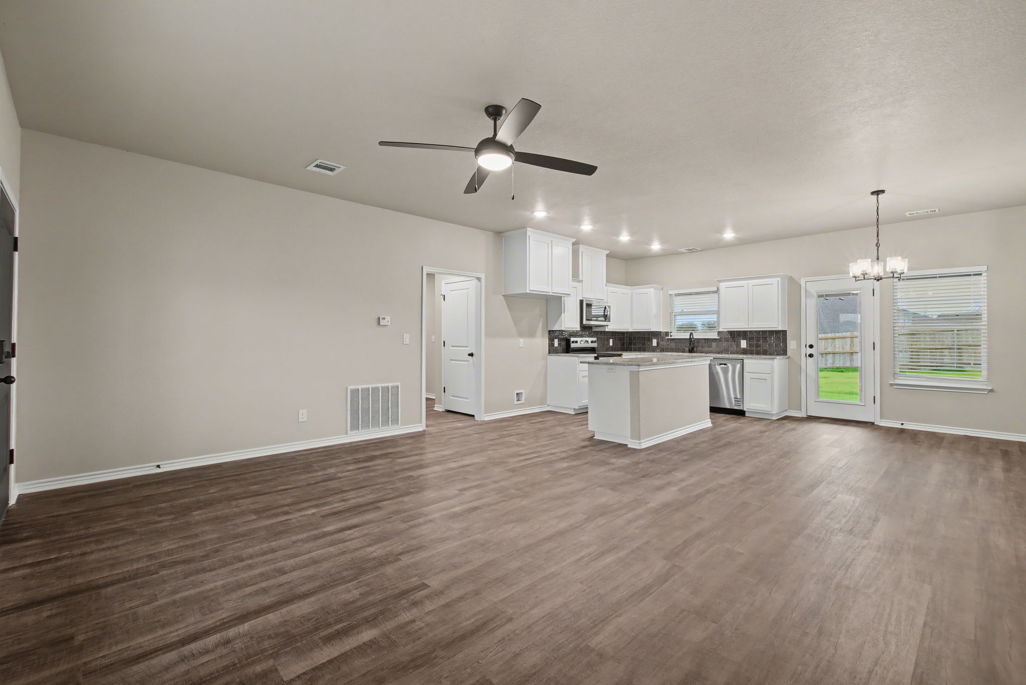 206 Water Wl Road Burnet, TX 78611 - Photo 4 of 25 An open-concept living area seamlessly connects to the modern kitchen with durable plank flooring.