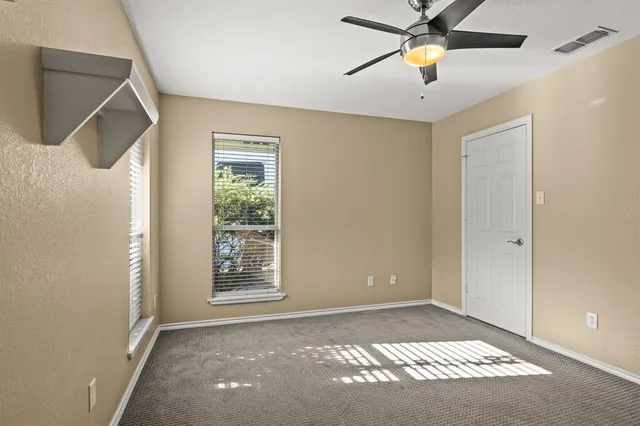 a view of an empty room with window and a ceiling fan