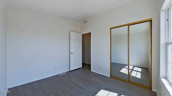 a view of an empty room with window and wooden floor