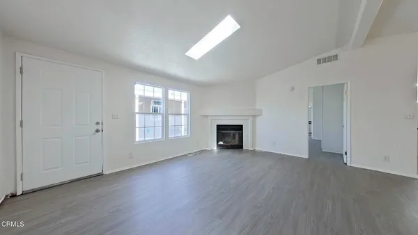 an empty room with wooden floor fireplace and windows