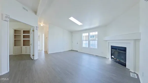 an empty room with wooden floor fireplace and windows