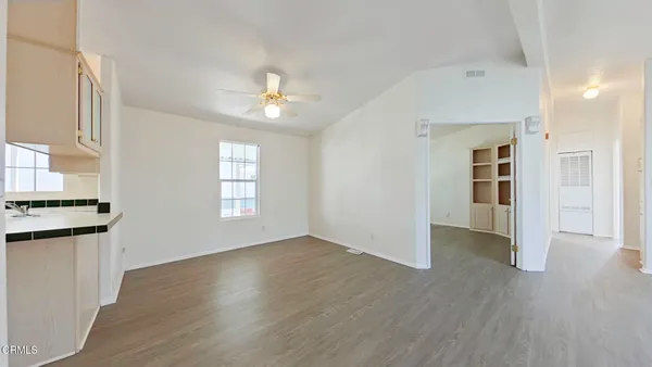 an empty room with wooden floor and a kitchen