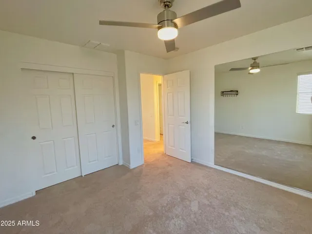 an empty room with closet and a ceiling fan