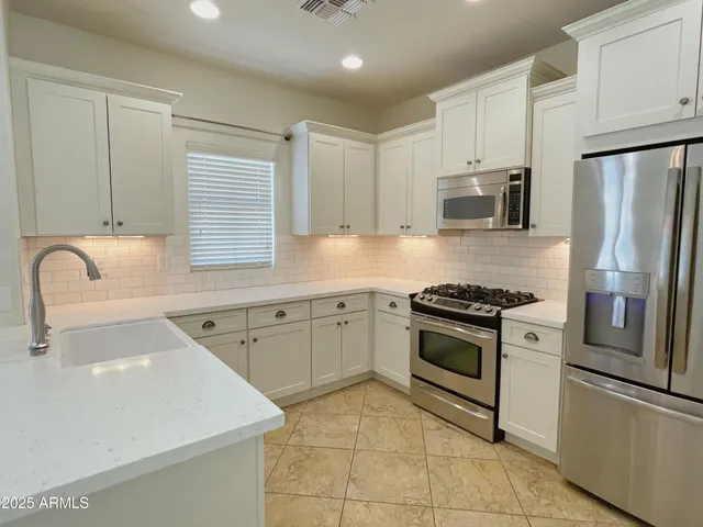 a kitchen with granite countertop a sink stainless steel appliances and cabinets