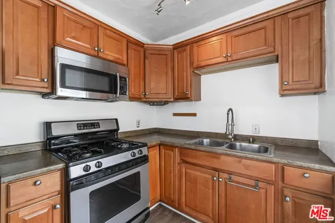 a kitchen with granite countertop a sink stove and microwave