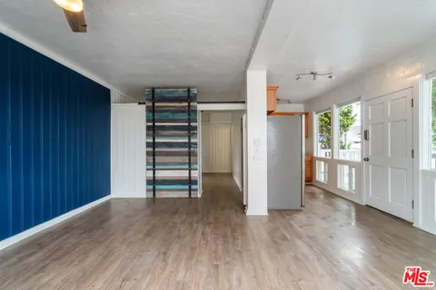 an empty room with wooden floor closet and windows