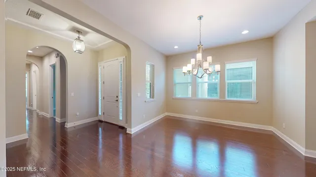 a view of a room with wooden floor chandelier and windows