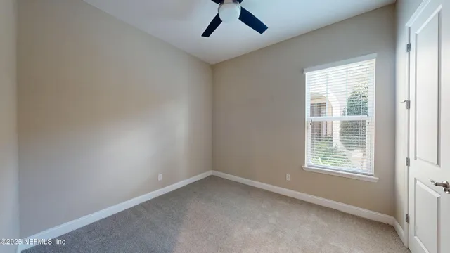 an empty room with a window and a ceiling fan