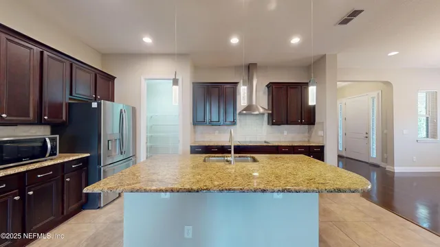 a kitchen with kitchen island granite countertop wooden cabinets and refrigerator
