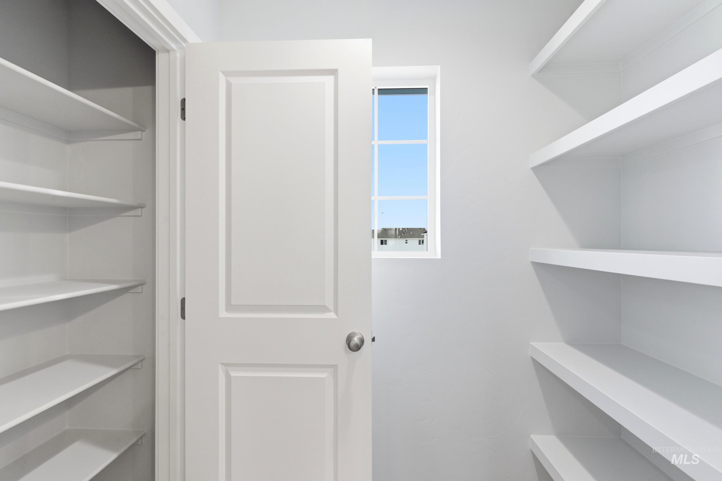 13709 Redway Court Caldwell, ID 83607 - Photo 23 of 28 Spacious pantry featuring extensive white shelving, a paneled door with a brushed nickel knob, and a window providing natural light