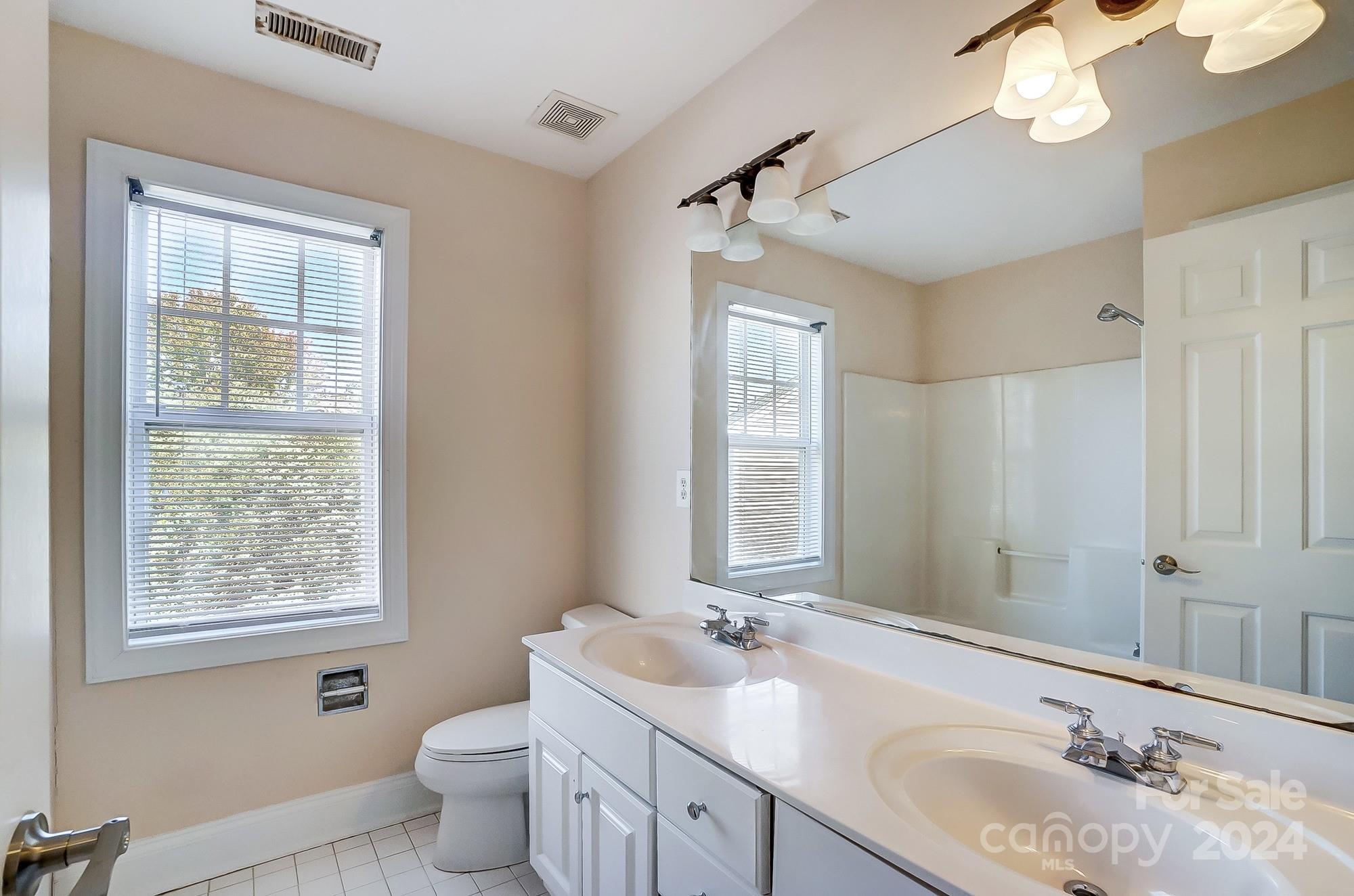 14137 Wild Elm Road Charlotte, NC 28277 - Photo 29 of 36 a bathroom with a granite countertop toilet a sink a mirror and a window
