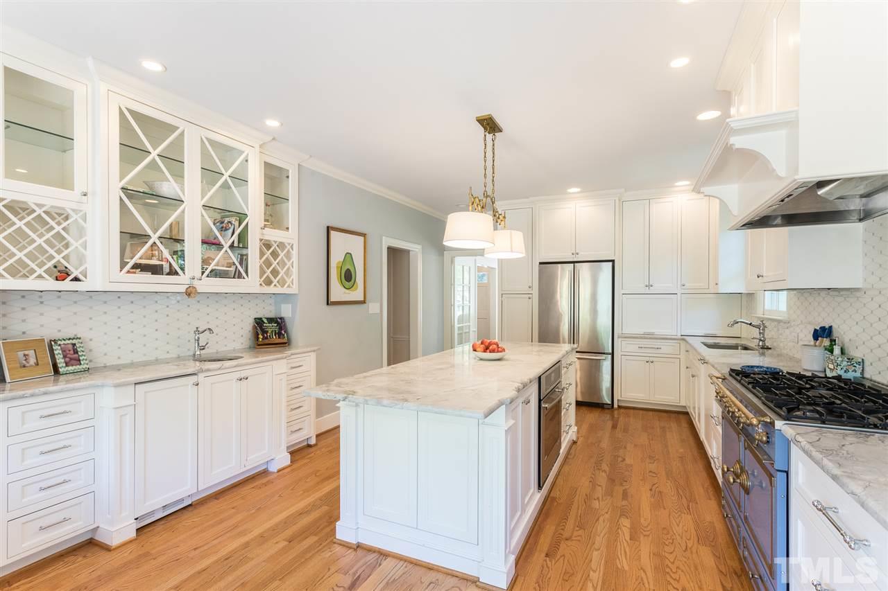 1424 Canterbury Road Raleigh, NC 27608 - Photo 14 of 29 a large kitchen with kitchen island a stove a sink a refrigerator and white cabinets with wooden floor