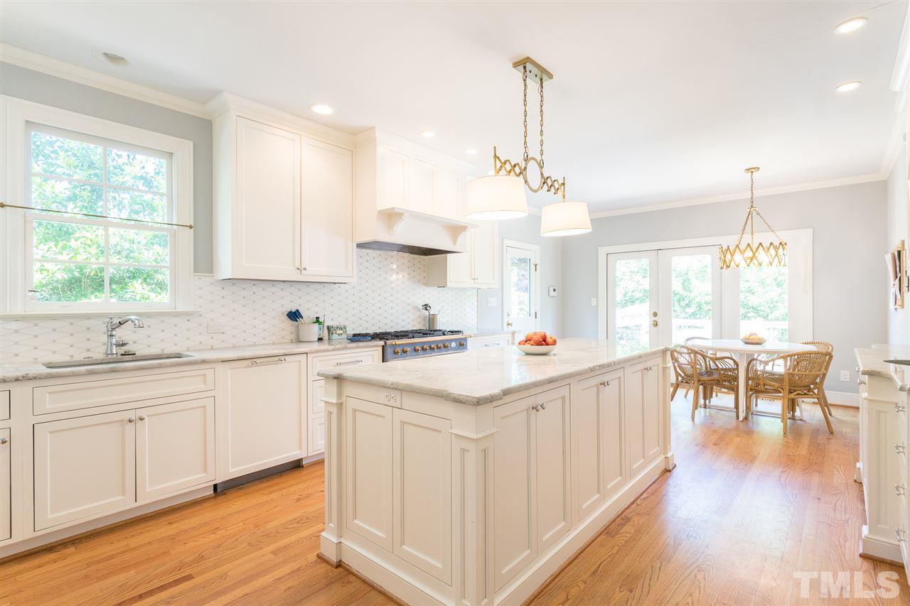 1424 Canterbury Road Raleigh, NC 27608 - Photo 9 of 29 a kitchen with stainless steel appliances granite countertop a stove and white cabinets with wooden floor