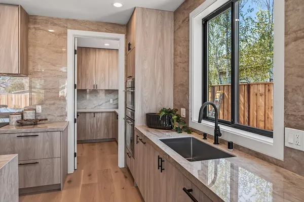 a kitchen with a sink a counter top space stainless steel appliances a large window and cabinets