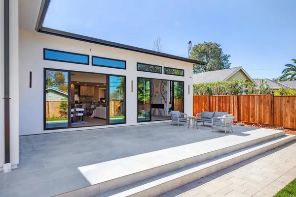 a view of house with chairs and floor to ceiling window and wooden fence