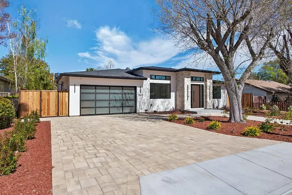 a front view of a house with garden and trees