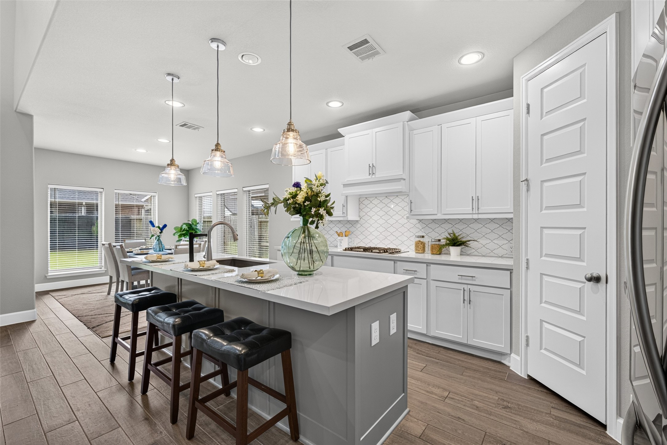 4207 Ana Ridge Lane Fulshear, TX 77441 - Photo 8 of 37 Gourmet kitchen featuring a spacious center island with seating, elegant pendant lighting, sleek white cabinetry, and stylish finishes.