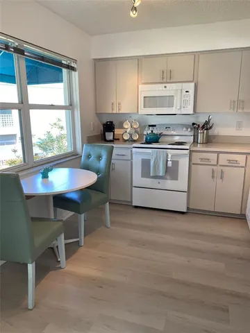 a kitchen with granite countertop white cabinets and white appliances