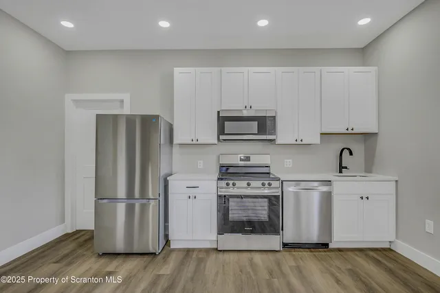 a kitchen with stainless steel appliances a refrigerator and a stove top oven