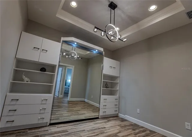 a view of a hallway with wooden floor and a ceiling fan