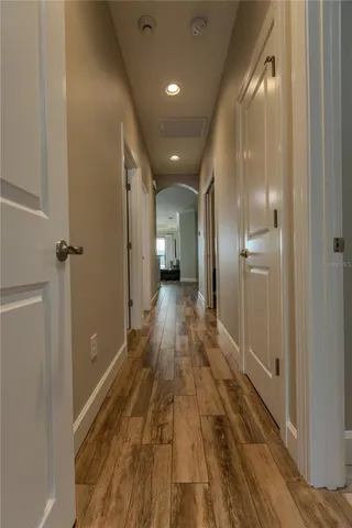 a view of a hallway with wooden floor and a bathroom