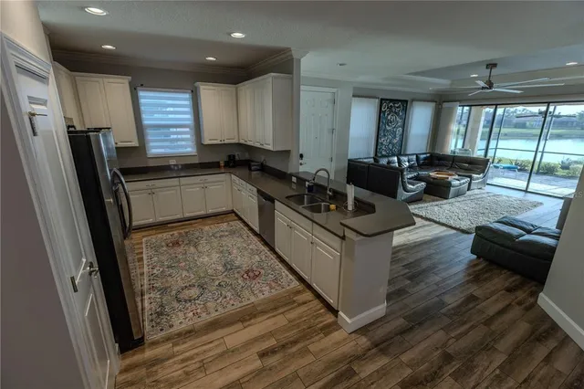 a kitchen with stainless steel appliances granite countertop a refrigerator a sink dishwasher a stove and white countertops with wooden floor