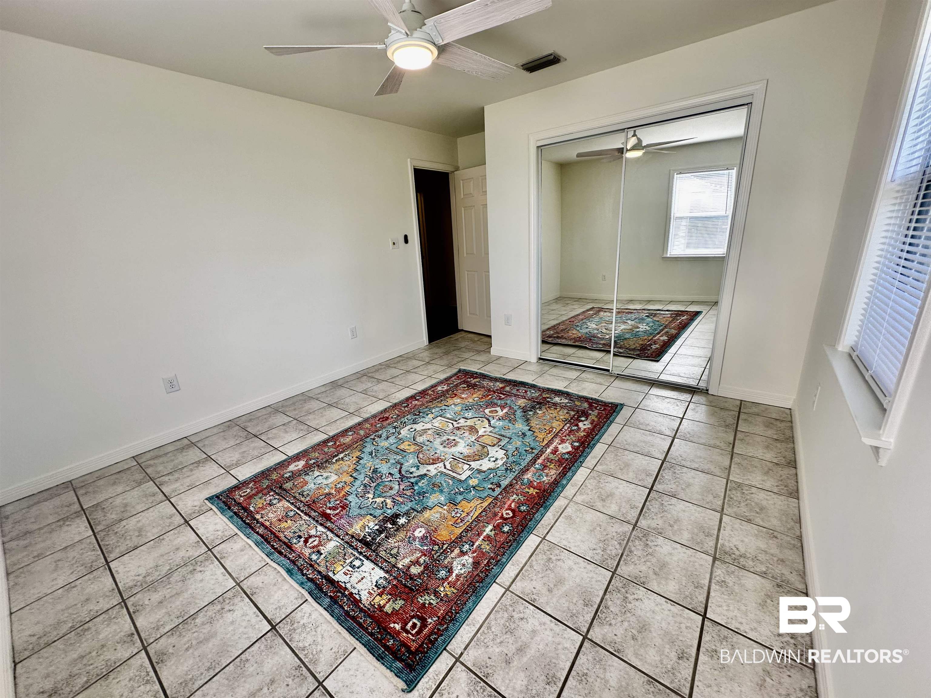 9090 Bay Pnes Road Elberta, AL 36530 - Photo 16 of 26 Unfurnished bedroom with ceiling fan, light tile patterned floors, and a closet