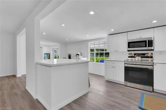 a kitchen with kitchen island stainless steel appliances a stove refrigerator sink and cabinets