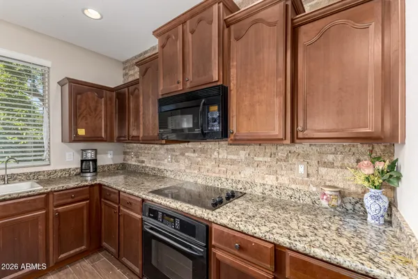 a kitchen with granite countertop a sink a stove and cabinets