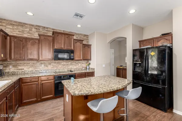 a kitchen with stainless steel appliances granite countertop a kitchen island hardwood floor sink stove and refrigerator