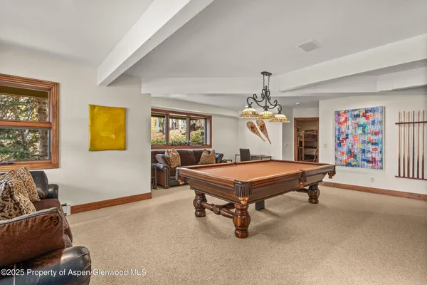 a room with furniture pool table flat screen tv and windows