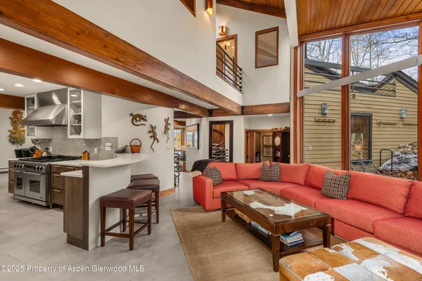 a living room with furniture a large window and stainless steel appliances