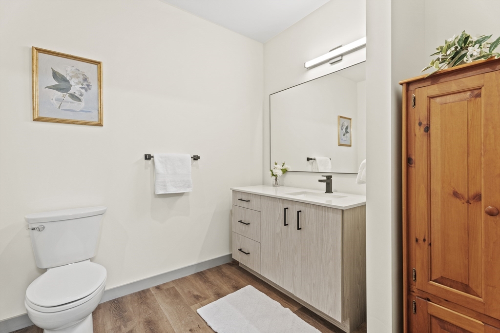 203 Lowell Street, Unit 103 Wilmington, MA 01887 - Photo 19 of 39 a spacious bathroom with a toilet a sink and mirror